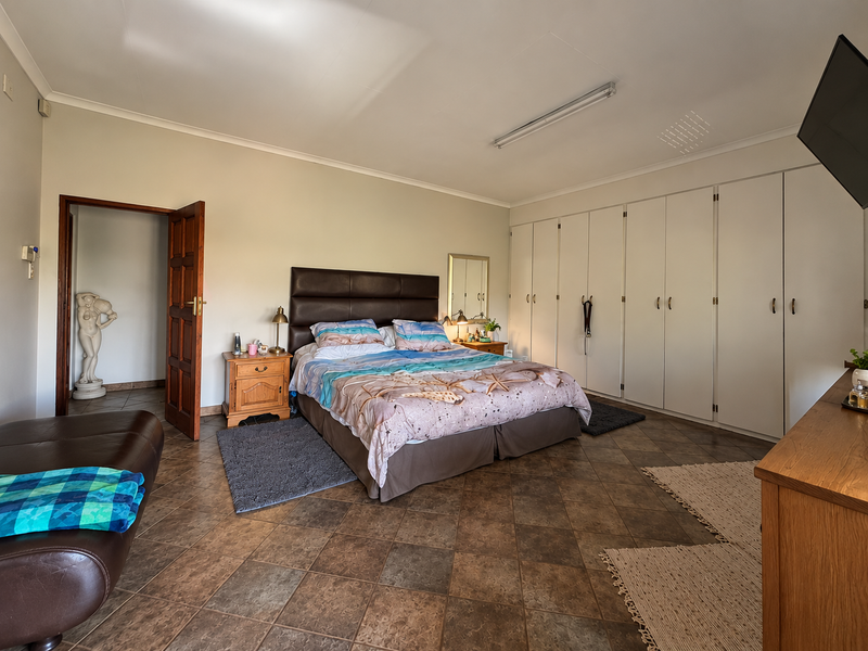 Spacious bedroom featuring extensive built-in cupboards, tiled flooring, and direct access to an adjoining room.