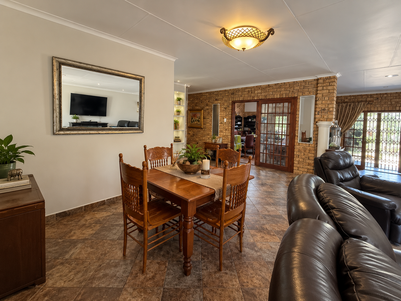 Spacious open-plan living and dining area featuring exposed brick walls, tiled flooring, and direct access to the outdoor patio through glass french doors.