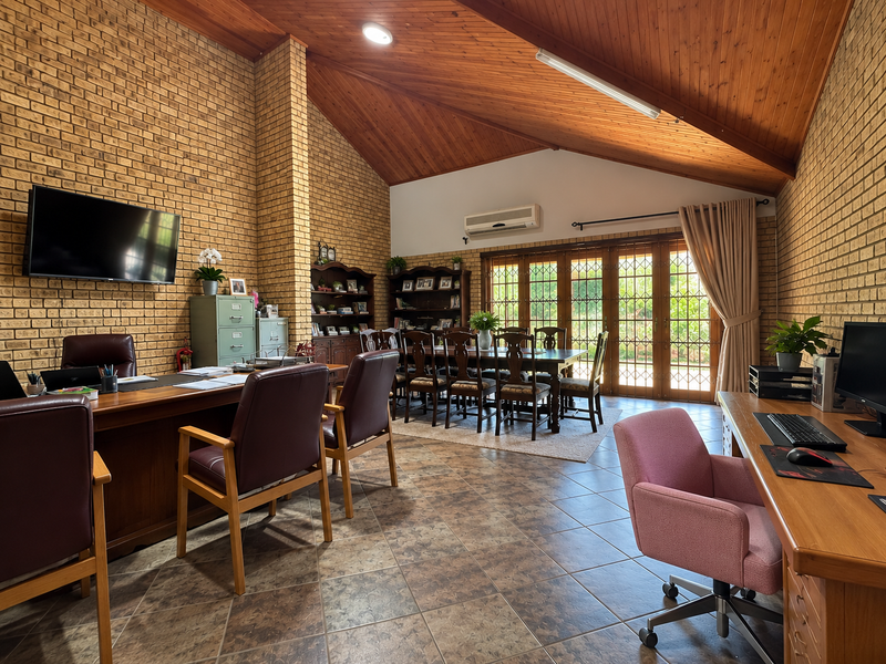 Spacious open-plan area featuring vaulted timber ceilings, exposed brick walls, and ceramic tile flooring, with direct access to the outdoors via folding glass doors.