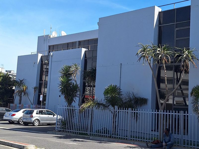 Exterior view of a commercial building featuring a modern facade with large glass windows and secure perimeter fencing.