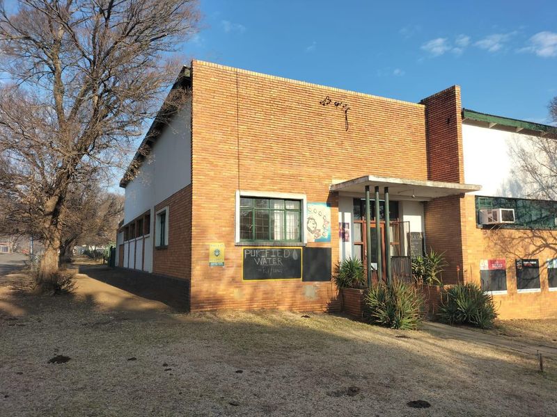 Front exterior view of a commercial face brick building featuring steel frame windows and a concrete entrance canopy.