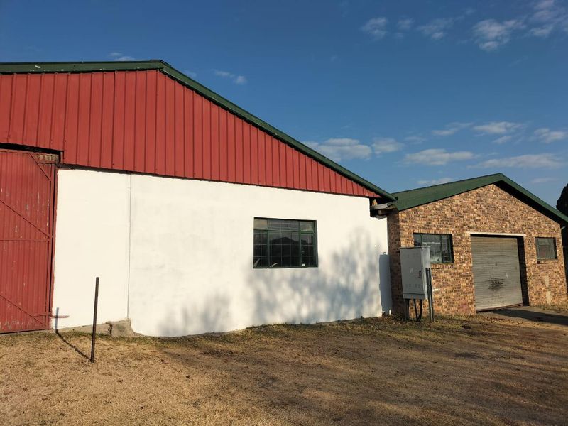 Exterior view of a commercial property featuring a combination of painted masonry and face brick walls with a roller shutter door and metal roofing.