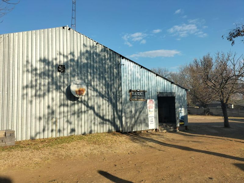 Exterior view of a commercial warehouse-style building featuring corrugated metal cladding, a satellite dish, and signage.