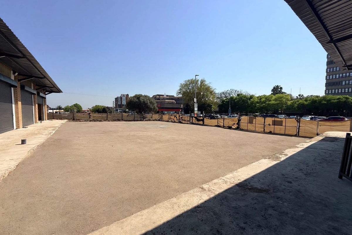 An expansive outdoor paved yard area featuring metal roof overhangs, roller shutter access, and perimeter fencing, suitable for commercial storage or parking.