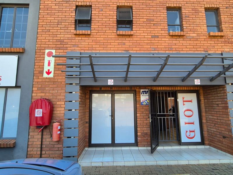 Front entrance of an industrial unit featuring a brick facade, metal awning, security gate, and integrated fire safety equipment.