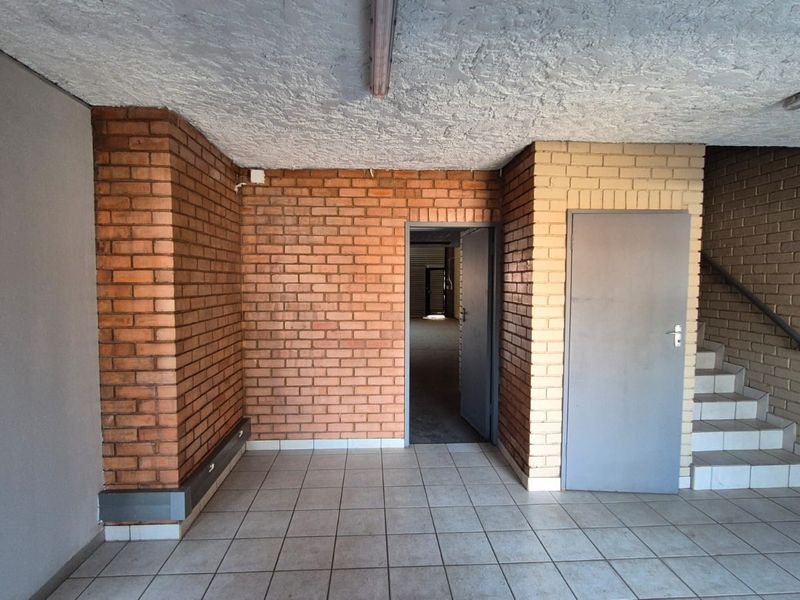 An industrial-style entry area featuring exposed brick walls, tiled flooring, and a staircase leading to an upper level.