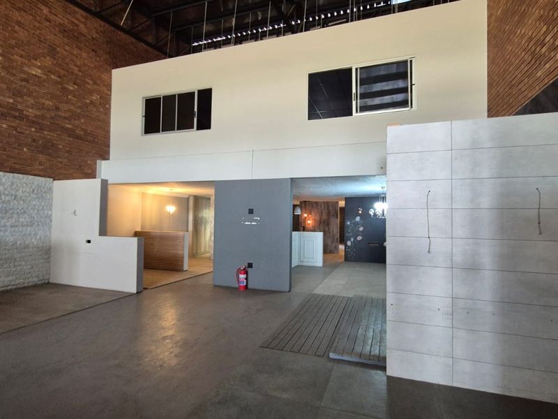 Spacious industrial open-plan area featuring exposed brickwork, concrete flooring, and a mezzanine level, offering a versatile layout for various commercial or creative uses.