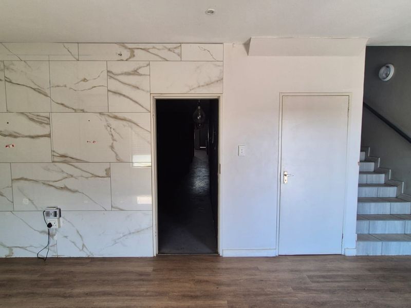 Spacious interior area featuring marble-effect wall tiling, laminate flooring, and an integrated staircase, offering a versatile layout for industrial or commercial use.