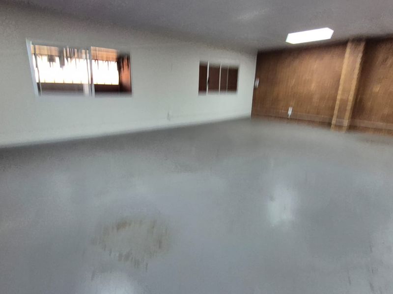 An empty industrial utility space featuring epoxy flooring, exposed brick walls, and functional overhead lighting.
