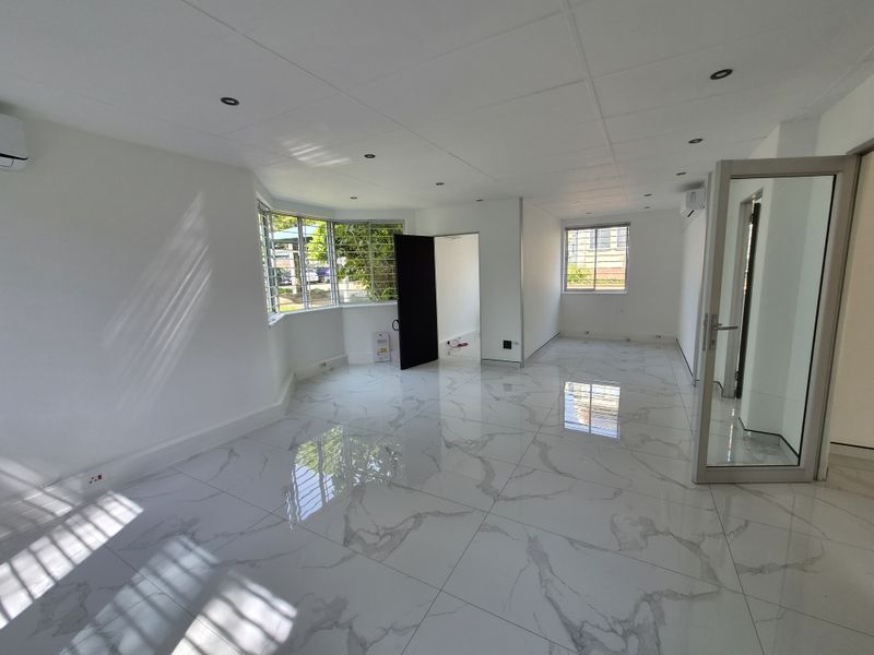 Bright and modern open-plan office space featuring polished marble-look floor tiles, recessed lighting, and split-system air conditioning.