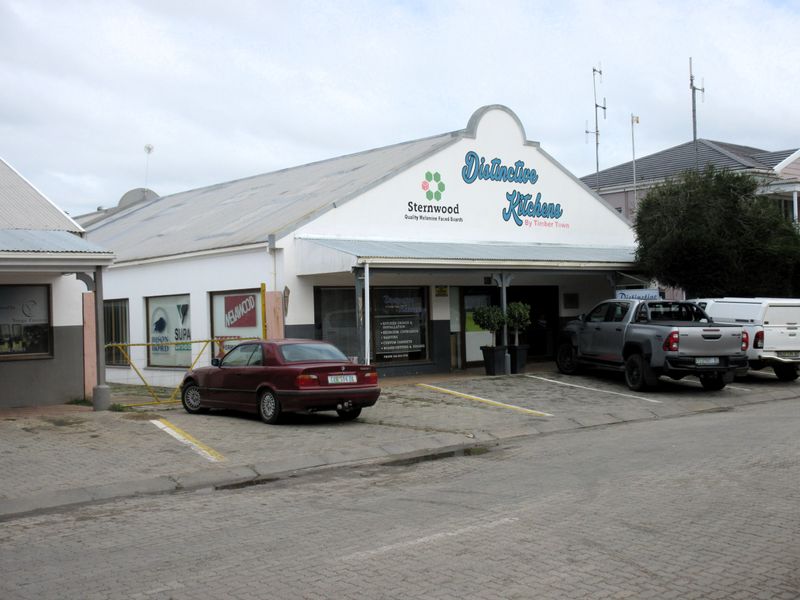 Front exterior view of a commercial building featuring a gabled roof, signage, and a paved parking area.