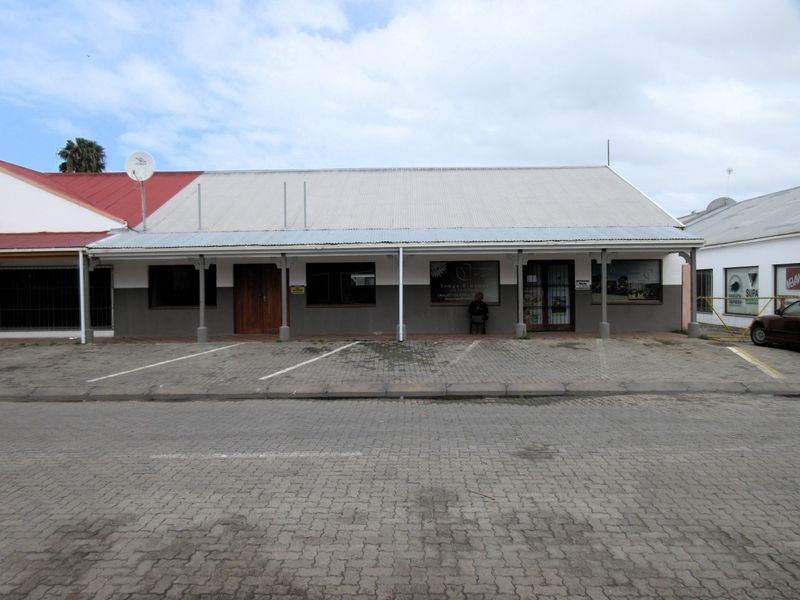 Front elevation of a commercial property featuring a covered veranda, paved parking area, and secure entrance doors.