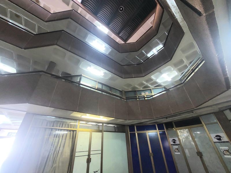 A multi-level office atrium featuring a central void, recessed lighting, and glass-partitioned office suites with metal framing.