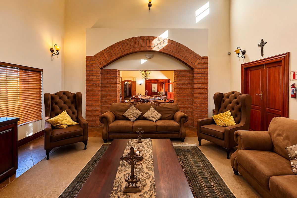 Spacious living room featuring a prominent exposed brick archway, double volume ceilings, and warm wall sconce lighting, creating an inviting and traditional atmosphere.