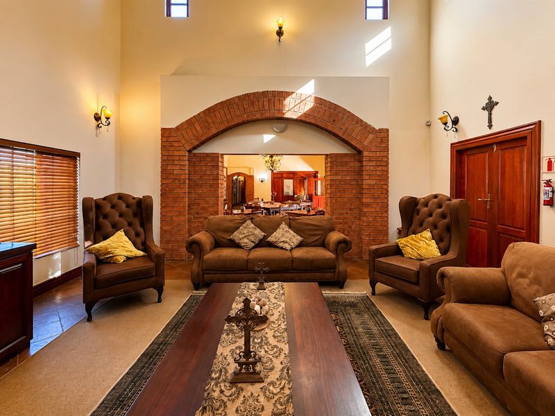 Spacious living room featuring a prominent exposed brick archway, double volume ceilings, and warm wall sconce lighting, creating an inviting and traditional atmosphere.