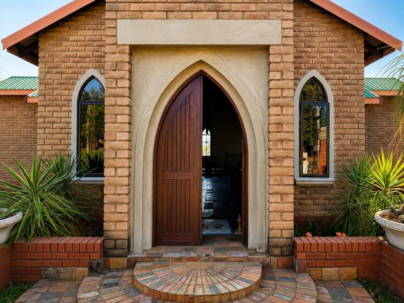 A charming entrance featuring a distinctive arched wooden door, brick facade, and decorative brick paving, showcasing classic architectural character.