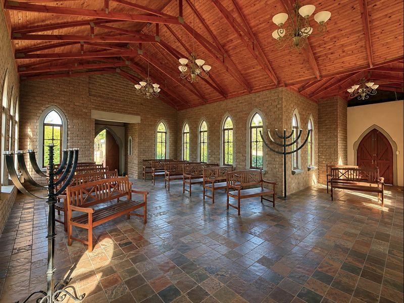 Spacious chapel or event hall featuring exposed timber truss ceilings, rustic brick walls, arched windows, and durable slate tile flooring.