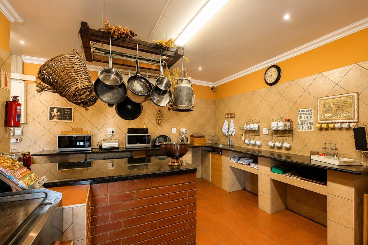A functional kitchen featuring granite countertops, brick-based cabinetry, and tiled finishes, equipped with a ceiling-mounted pot rack and ample workspace.