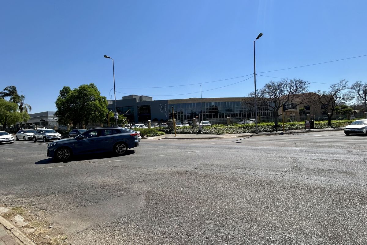 A street-level view of the commercial property frontage, showing the surrounding road infrastructure and perimeter fencing.