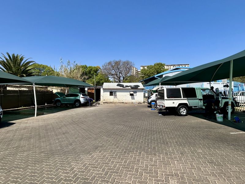 Commercial vacant land featuring a paved parking area with shade cloth carports and a small outbuilding structure.