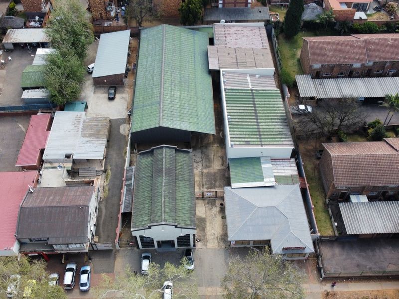 Aerial view of an industrial property complex featuring multiple warehouse structures with corrugated metal roofing and paved access areas.