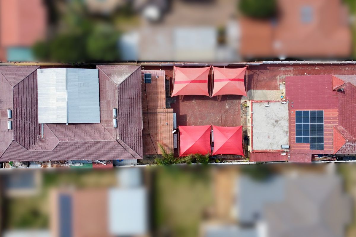 Aerial view of the property showing the roof layout, solar panel installation, and covered parking areas with shade sails.