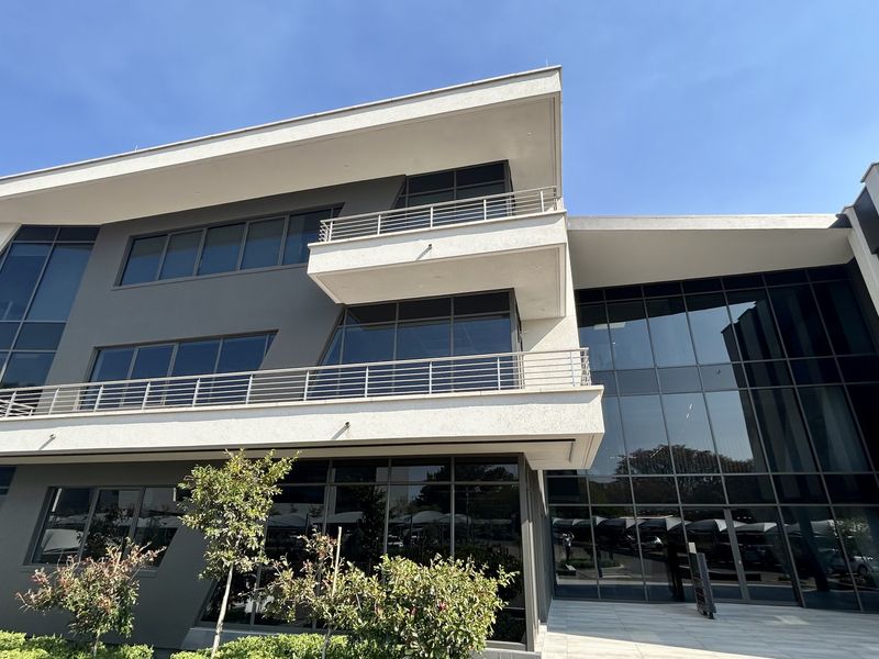 Modern multi-story office building featuring a contemporary glass curtain wall facade and integrated balconies with metal railings.