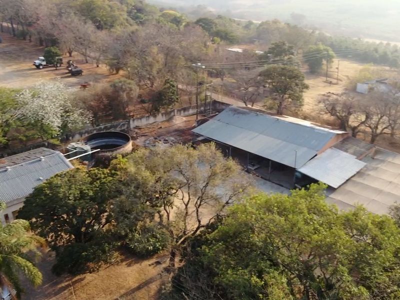 Aerial view of the small holding property featuring multiple outbuildings, corrugated metal roofing, and a water storage tank set within a rural landscape.
