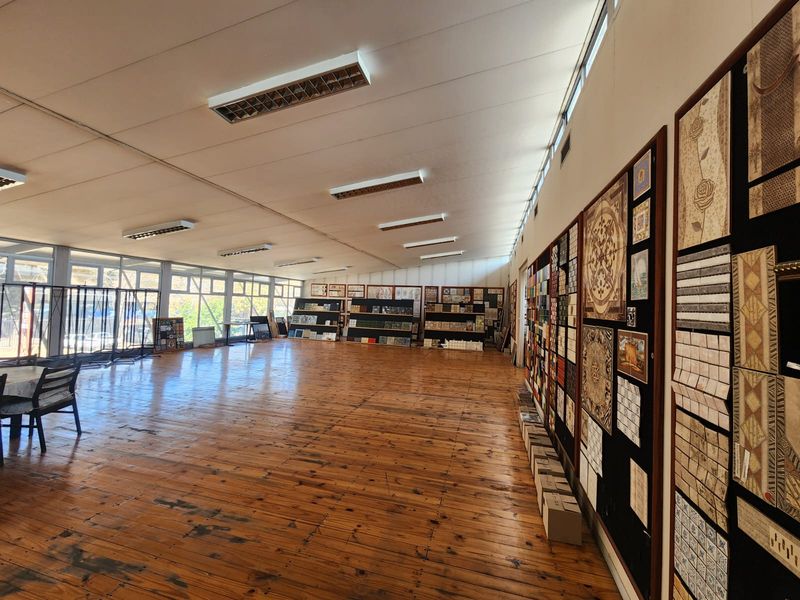 Spacious open-plan industrial showroom featuring polished timber flooring, extensive natural light from large windows, and integrated wall-mounted display panels.