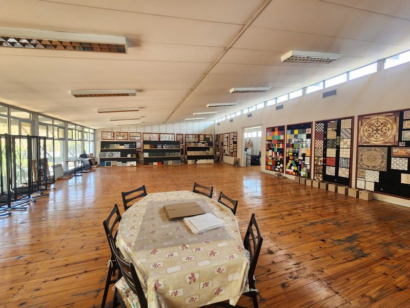 Spacious industrial showroom featuring timber flooring, extensive natural light from large windows, and wall-mounted display panels for product presentation.