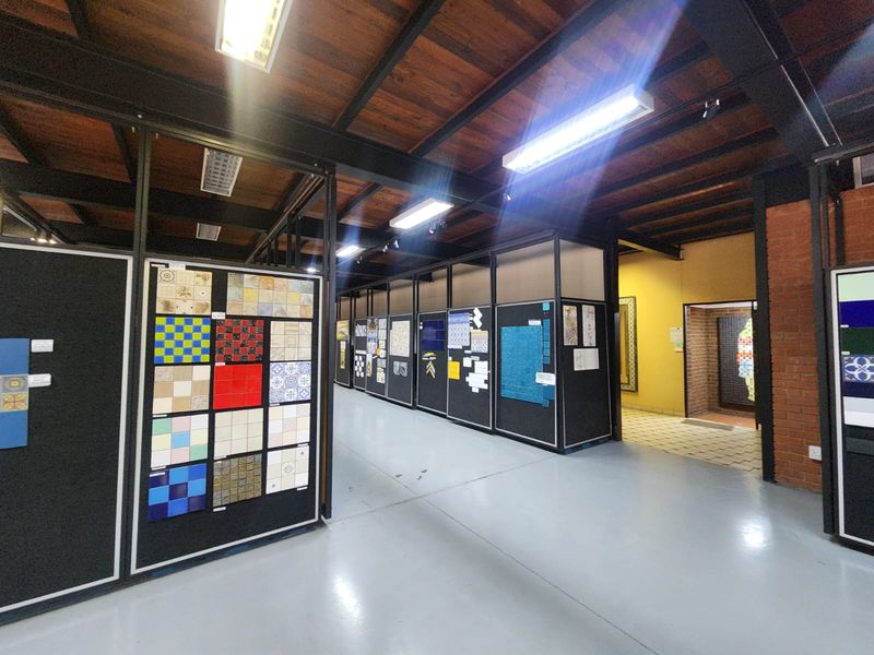Industrial style showroom or commercial space featuring exposed timber ceilings, steel beams, epoxy flooring, and modular partition walls for product display.