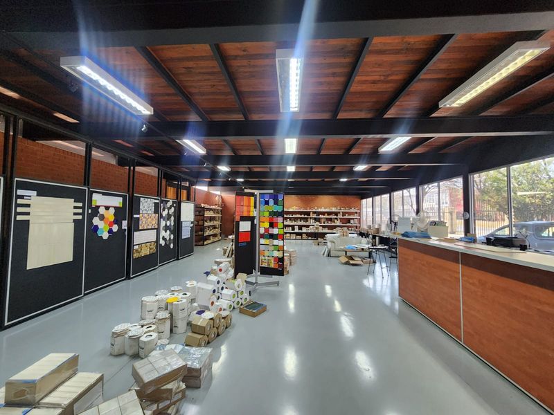 Spacious industrial showroom featuring exposed timber ceilings, steel structural beams, polished epoxy flooring, and large glass windows providing ample natural light.