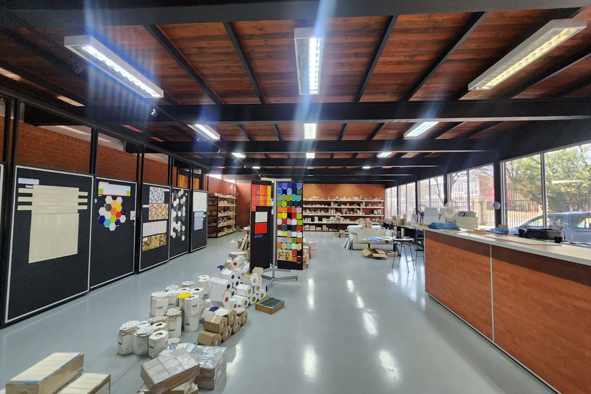 Spacious industrial showroom featuring exposed timber ceilings, steel structural beams, polished epoxy flooring, and large glass windows providing ample natural light.