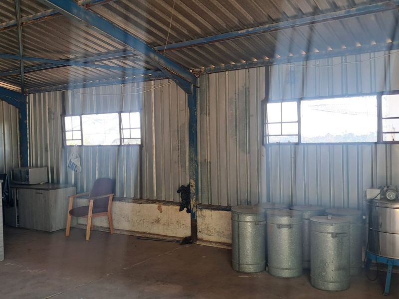 Industrial utility space featuring corrugated metal walls, exposed steel roof trusses, and concrete flooring, suitable for storage or workshop use.