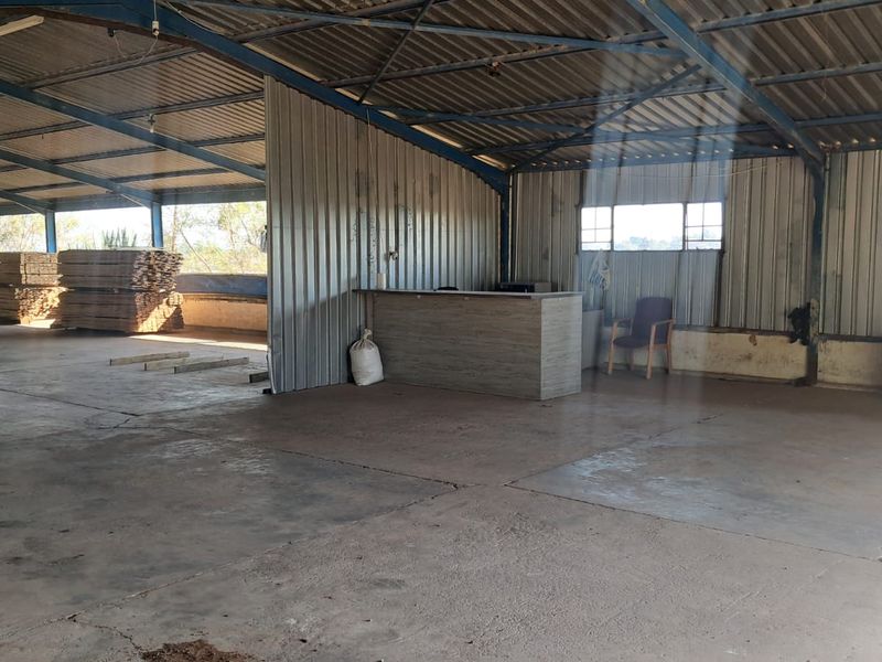 Spacious industrial utility area featuring corrugated metal walls, exposed steel roof structure, and durable concrete flooring with a built-in service counter.