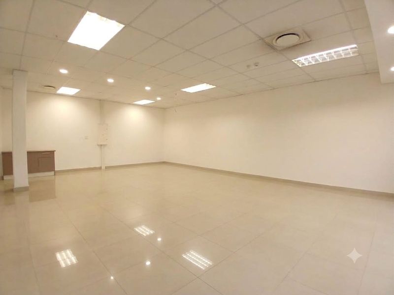 A spacious, open-plan retail unit featuring polished tiled flooring, a suspended ceiling with recessed lighting, and integrated air conditioning.