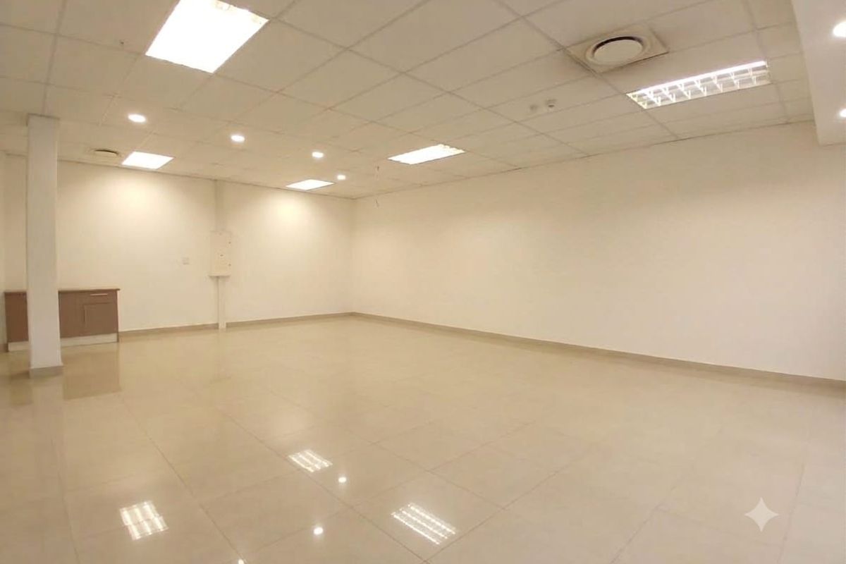 A spacious, open-plan retail unit featuring polished tiled flooring, a suspended ceiling with recessed lighting, and integrated air conditioning.