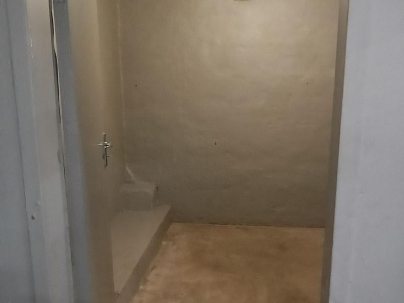 A small, utilitarian storage or utility space featuring a concrete floor and exposed ceiling, suitable for general storage or workshop use.