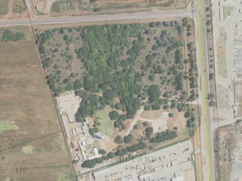 Aerial view of a large commercial vacant land parcel featuring mature vegetation and established access points, suitable for future development.