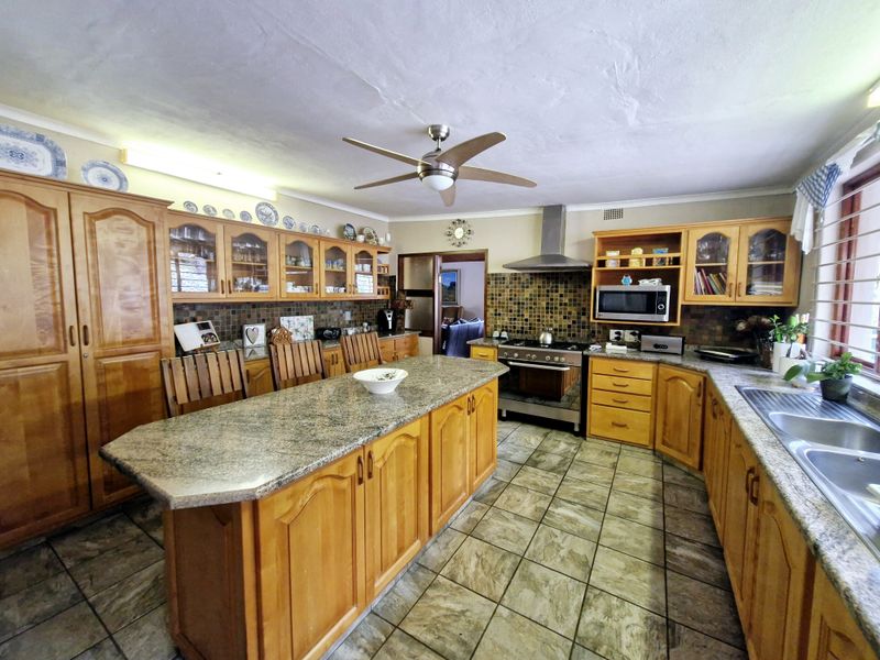 Spacious kitchen featuring solid wood cabinetry, granite countertops, a central island, and built-in appliances, offering a functional layout with ample storage space.