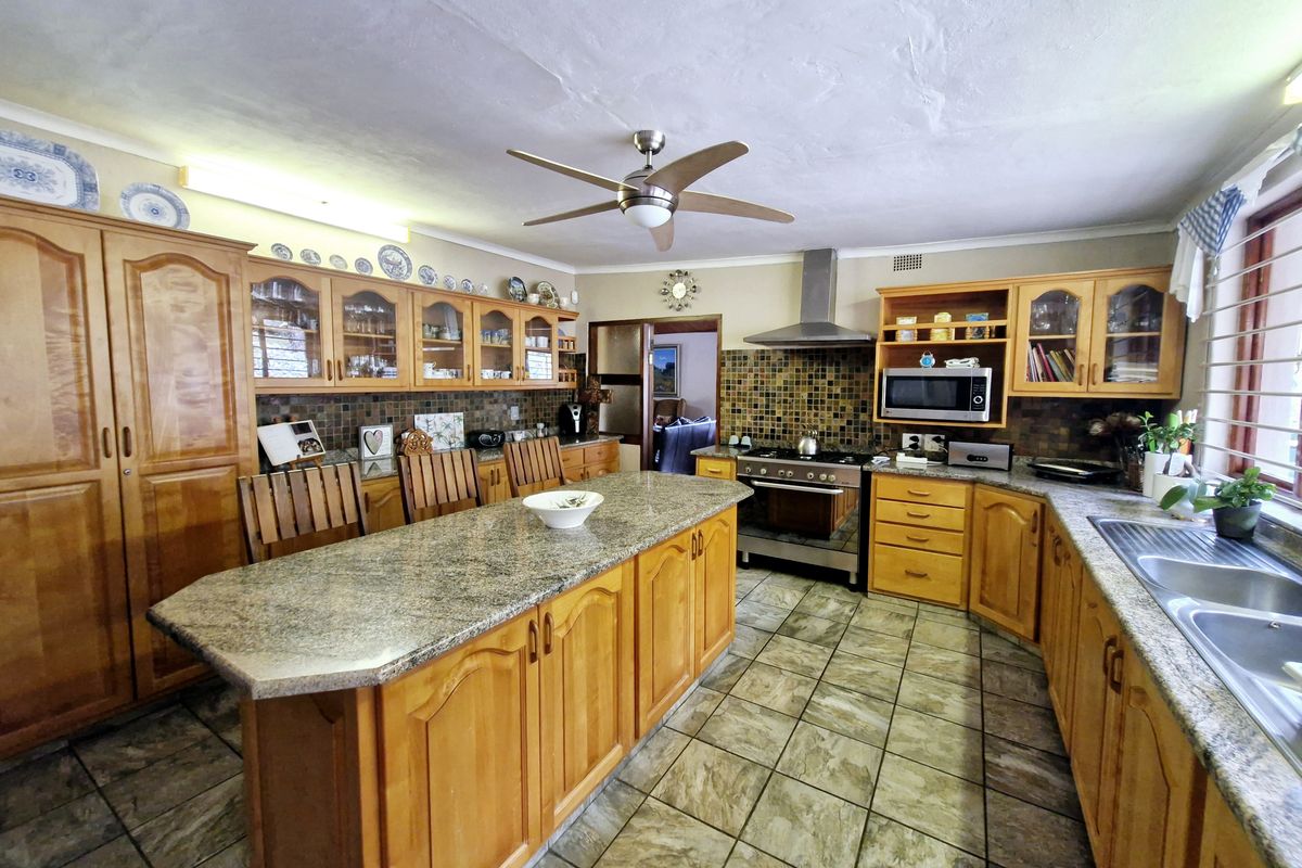 Spacious kitchen featuring solid wood cabinetry, granite countertops, a central island, and built-in appliances, offering a functional layout with ample storage space.