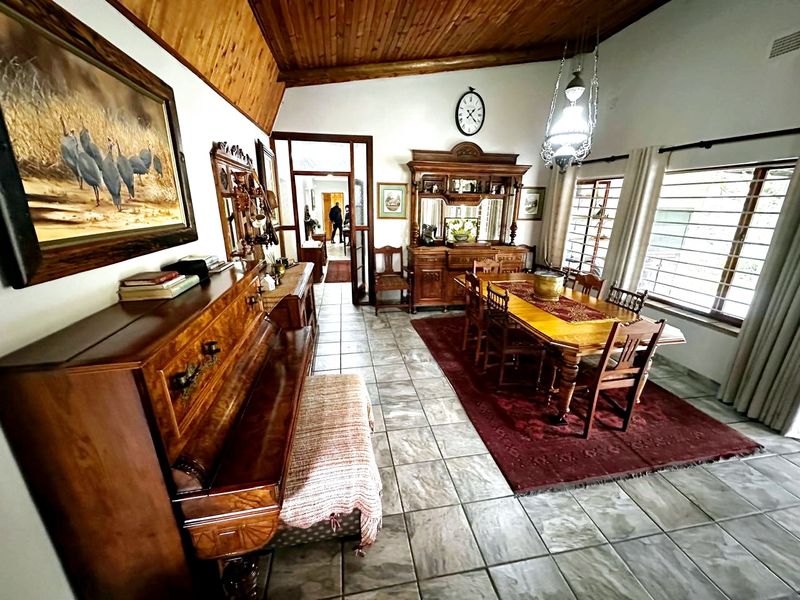 Spacious dining room featuring tiled flooring, exposed timber ceiling, and large windows with security bars, offering a traditional aesthetic.