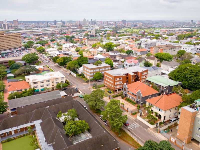 An elevated aerial view showcasing the surrounding urban landscape, neighborhood infrastructure, and city skyline.