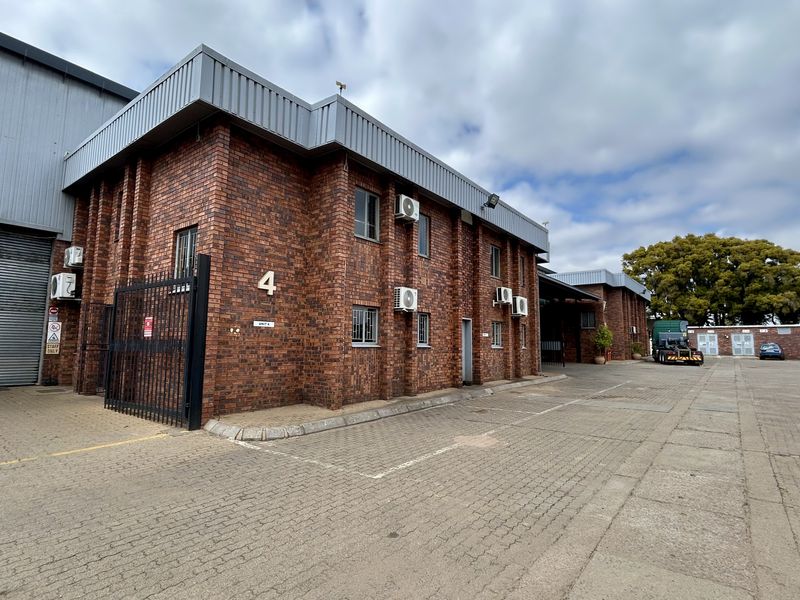 Industrial unit featuring a brick facade, roller shutter door, and paved driveway access within a secure complex.
