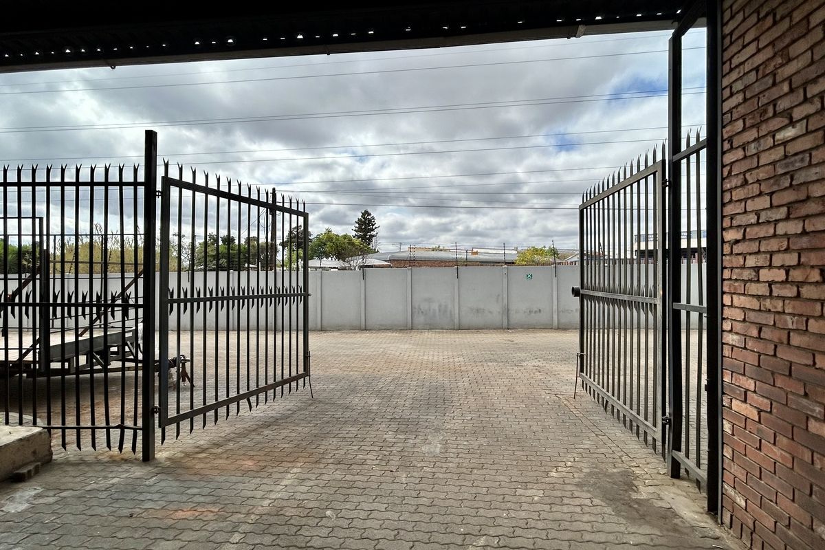 A secure industrial yard area featuring paved surfacing, perimeter walling, and large metal security gates for vehicle access.