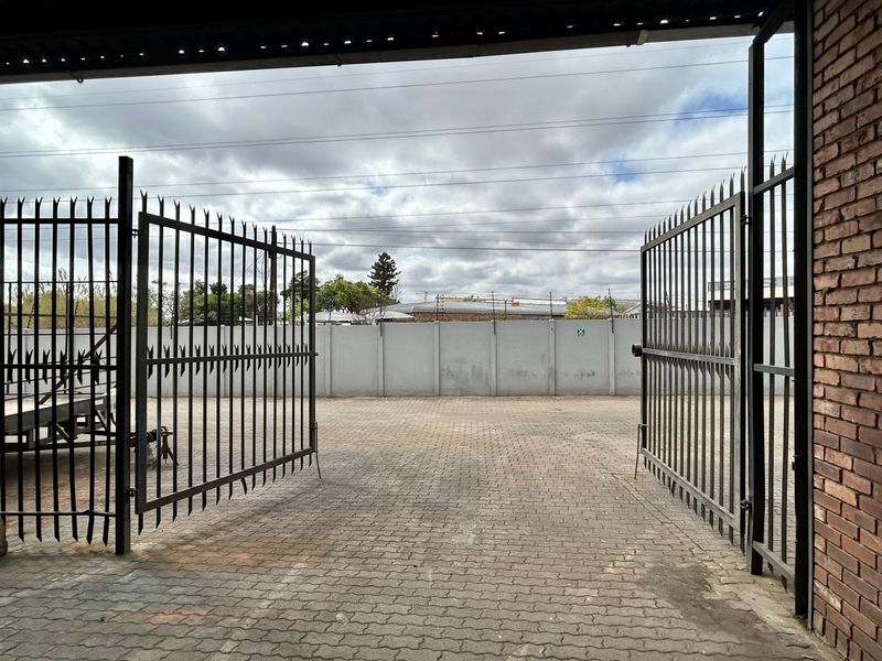 A secure industrial yard area featuring paved surfacing, perimeter walling, and large metal security gates for vehicle access.