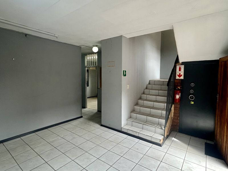 Industrial entry foyer featuring tiled flooring, a staircase with a metal handrail, and a secure access door.