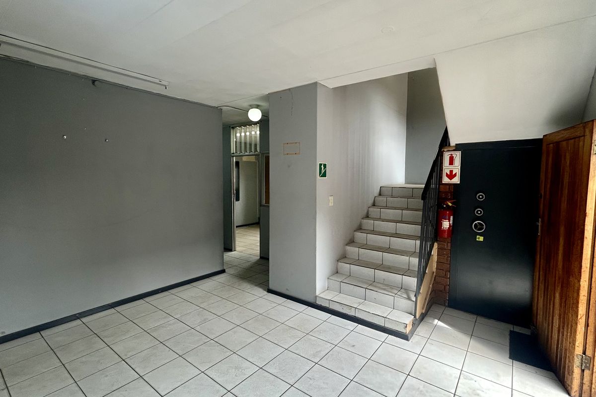 Industrial entry foyer featuring tiled flooring, a staircase with a metal handrail, and a secure access door.