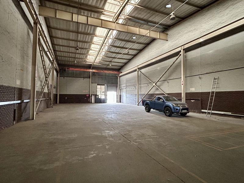 Spacious industrial warehouse featuring high ceilings with exposed steel trusses, skylights for natural light, and durable concrete flooring.