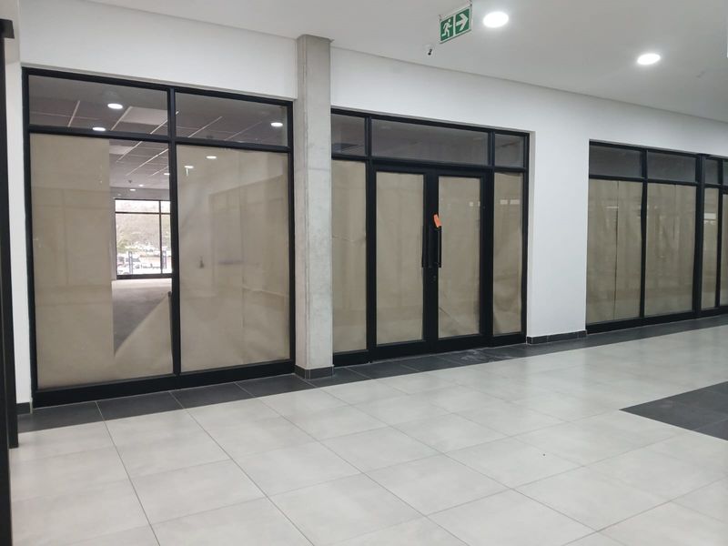 Modern vacant office space featuring large black aluminium framed windows and doors, tiled flooring, and recessed lighting in a clean, professional commercial environment.
